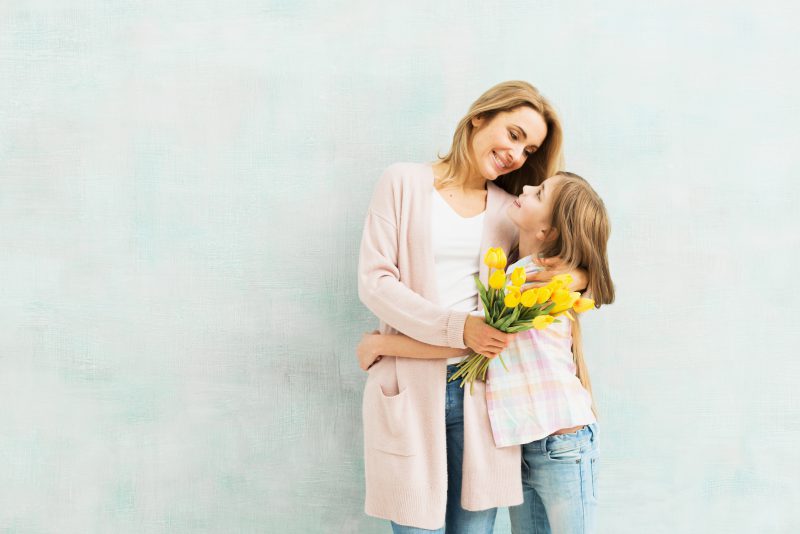 matka stoi z córką z kwiatami na dzień matki