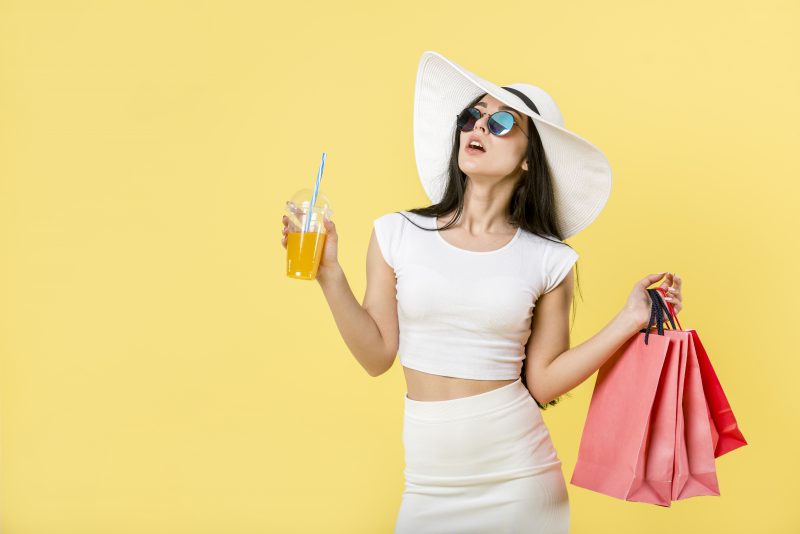 kobieta-w-białym-kapeluszu-trzyma-drinka-i-torby-z-zakupami