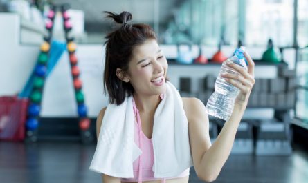 uśmiechnięta-kobieta-trzyma-butelkę-wody-po-treningu