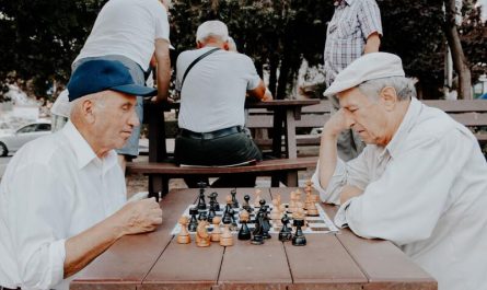 starsi ludzie graja w szachy w parku